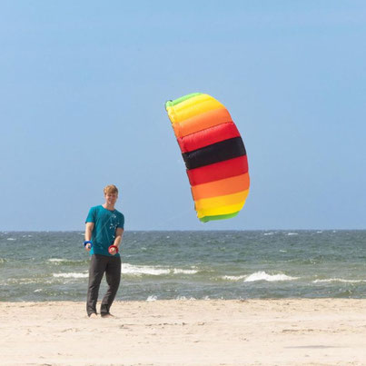 Mann lässt bunten Drachen am Strand fliegen