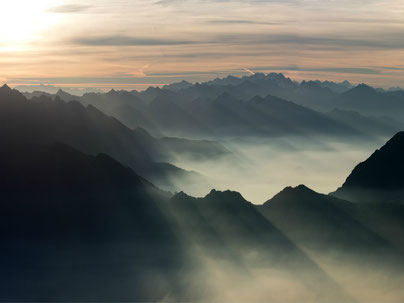 Foto orizzontale del sole che sorge sulle montagne vista dalla cima della Grigna a giugno