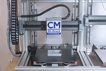 Eigenentwickelter 3D-Drucker. Konstruktion Aluprofile. Schwarzes Druckbett auf zwei Schienen vor und zurück fahren. Druckkopf einer Schiene links und rechts fahren. Links/rechts Gewindespindeln für hoch runter. Kabel links.
