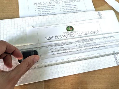 Hand, die gerade dabei ist, ein Papier mit einer mechanischen Scheidemaschine zu zerteilen
