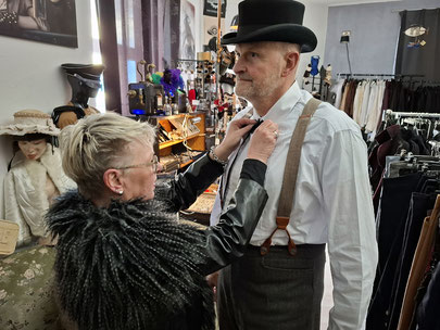 Ein Paar beim gemeinsamen Anlegen und Kombinieren eines Steampunk-Outfits für Anfänger im Ladengeschäft in Bochum