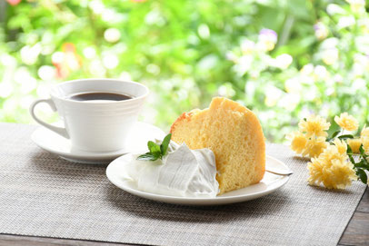 生クリームとミントの葉が添えられたシフォンケーキのお皿。コーヒーの入ったカップ&ソーサ。