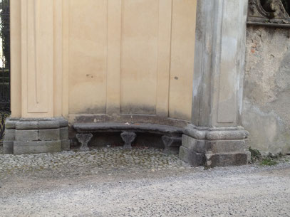 Panchina in pietra in fianco a cancello di ingresso edificio storico
