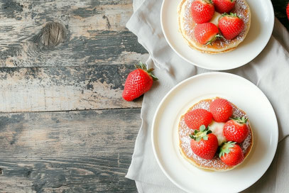 いちごがのったパンケーキのお皿が２つ並んでいる。