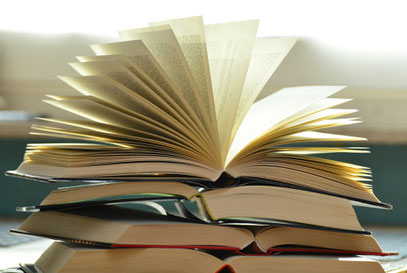 Ein Stapel aufgeschlagener Bücher: Lesen hilft dabei, gute Texte zu schreiben
