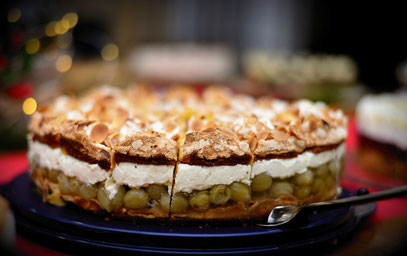 Eine sehr lecker aussehende Stachelbeertorte, von der Seite gezeigt, so dass die Baiserschicht oben etwas in der Unschärfe verschwindet. Deutlich sieht man den Boden, die Stachelbeerschicht, die Sahne und die Baiserschicht obenauf.