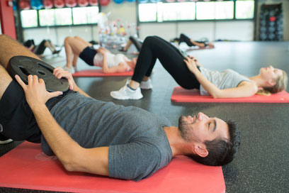 Sportler machen Beckenbodenübungen in einem Gymnastikraum