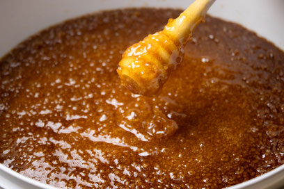 Cuillère de Miel dans le quel se trouve du Miel de Manuka NPA 15+ de Nouvelle-Zélande dans un seau de 10 kg de la marque Puri New Zealand