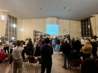 Großer Kirchensaal der EFG Tempelhof, viele Menschen schauen stehend nach vorne, an der Wand ist der Text eines Liedes zu sehen