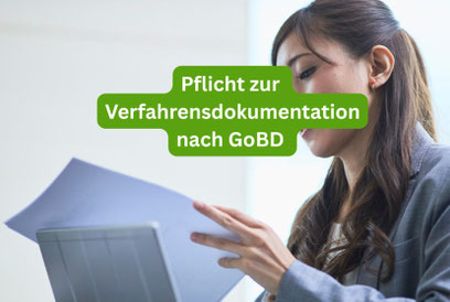 Junge Frau mit dunklen Haaren und einem hellgrauen Hosenanzug sitzt vor einem Laptop in hellem Raum blickt in ein Dokument. Das Bild hat den Schriftzug Pflicht zur Verfahrensdokumentation nach GoBD in weiss mit grüner Umrandung. 