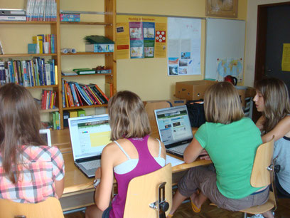 Rückansicht von Kindern, die an Laptops arbeiten.