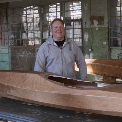Kursteilnehmer aus Kajakbau Workshop steht vor seinem fertigen Kajak gebaut aus Holz