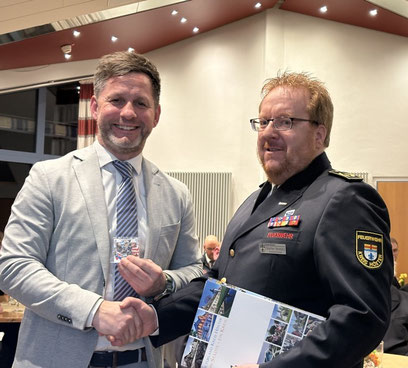 Der Kreisbrandmeister Stefan Nostitz übergibt Beverungens Bürgermeister den "Respekt"-Pin als sichtbares Zeichen der Wertschätzung und Solidarität mit Einsatzkräften.