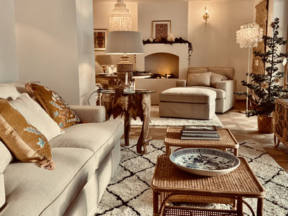 Luxuriöses Wohnzimmer mit großem Sofa und Sessel mit Hocker, Beistelltischen und Kamin. Helle Farben und natürliche Materialien wie Bambus, rattan und Baumwolle. Dicke Teppiche auf dem Schloss-Parkettboden aus Eiche.