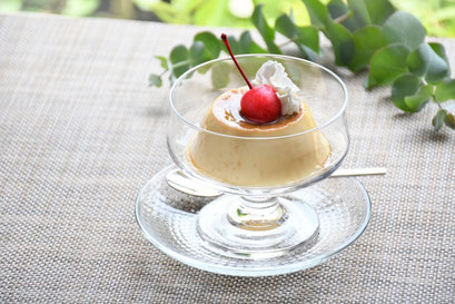 生クリームとさくらんぼが添えられたプリン。ガラスの器。