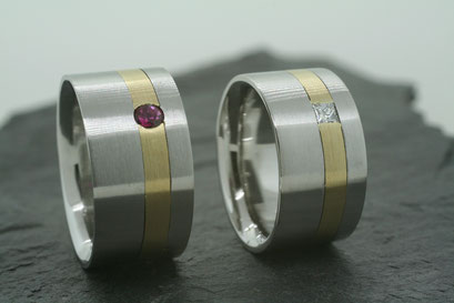 Trauringe / Eheringe aus Edelstahl im Bürst-Schliff mit Einlage aus Gelbgold und jeweils einem Rubin und Prinzessdiamant