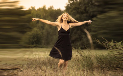 Frau in schwarzem Kleid läuft durch die Natur – künstlerisches, bewegtes Portrait in Erlangen