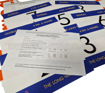 Custom printed Tyvek runner race bib numbers showing reverse printed medical and emergency contact information for the OUTRUN running event.