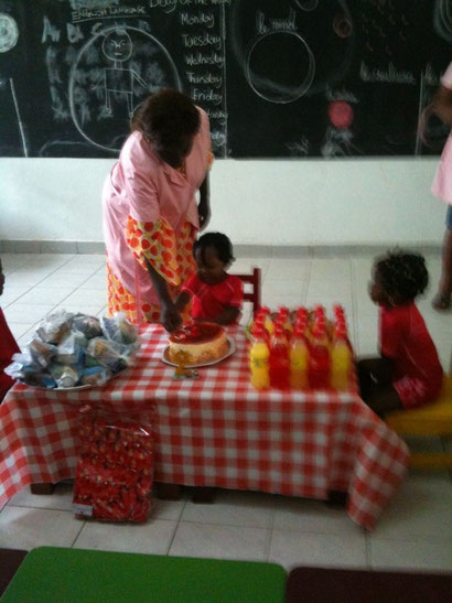 assistée par Mme Djengué, Emmanuelle coupe son gâteau  