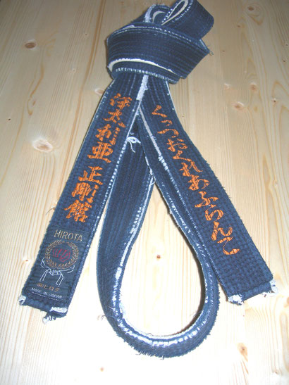 Cintura nera consegnata da Sensei Sadanobu Tatsuto a Sensei Francesco Cuzzocrea con su scritto Italia Seigokan a sinistra ed a destra Francesco Cuzzocrea