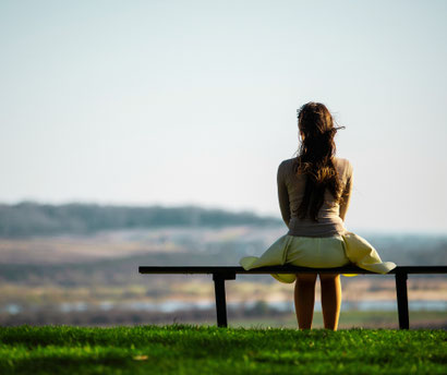 Eine einsame Frau sitzt auf einer Bank und blickt in die Landschaft. Wenn Hochsensibilität (HSP) Raum und Verständnis braucht, um emotionale Labilität zu verhindern – mein schützling.