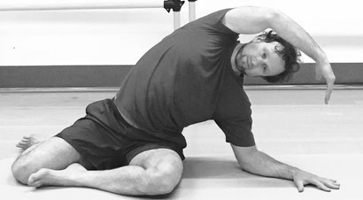 Man relieving back tension with the elongating relief of Pilates Seated Side Bend mathwork at STUDIO ORIGIN Bespoke Pilates in Newberg Oregon.