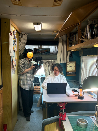 キャンピングカーの工房でJimdoHP 制作会社から取材を受けている男性