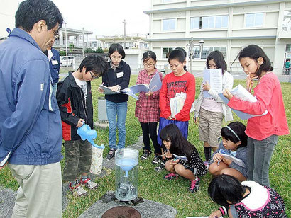 雨量計の仕組みについて学ぶ児童たち=26日午前、石垣島地方気象台