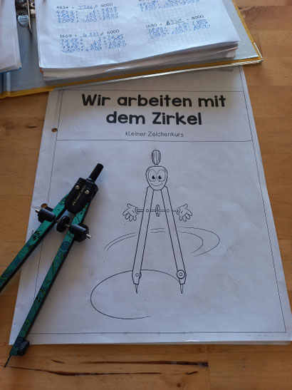 Lernhefter mit Zirkel und Ordner auf Esstisch