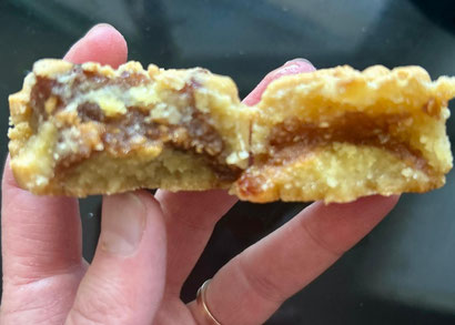 Makroud sans gluten moulés, garnis de pâte de dattes et imbibés de miel, présentés sur une assiette avec boutons de rose.