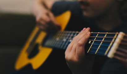 A man holding and playing a guitar. Playing guitar is a good, constructive form of distraction