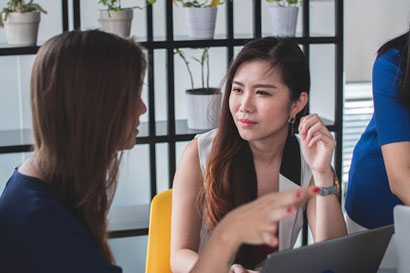 Two women speaking. The woman whose face we see seems to be listening intently. Focusing on what the other person is saying is an important part of mindful listening.