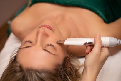 Femme en institut de beauté qui reçoit un soin visage avec appareil nouvelle technologie