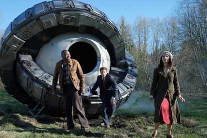 Image of main characters from the NBC show Timeless, standing in front of creepy looking Time Machine.