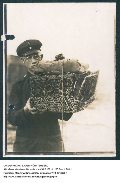 Foto eines Soldaten, der einen für den Flugzeugabwurf vorbereiteten, gepolsterten Taubenkorb trägt