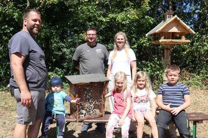 Kinder und Eltern vor dem Insektenhotel und dem Vogelfutterhäuschen