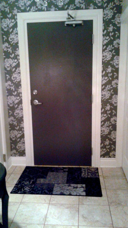 charcoal floral wallpaper and a charcoal painted door make an elegant entrance