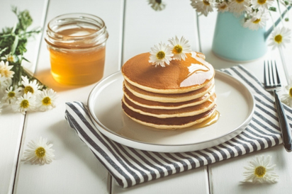 パンケーキのお皿。ストライプ模様のナプキン。蜂蜜の瓶。カモミールの花。