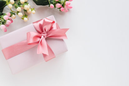 ピンク色のリボンがかけられたギフトボックス。バラの花のつぼみ。