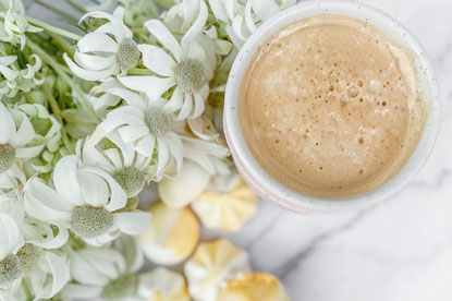 お皿に盛りつけられたたくさんのミニクロワッサン。カフェラテのマグカップ。白の花が咲いた小枝。