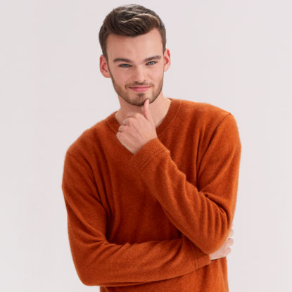 Mann lächelt in einem kuscheligen Pullover in die Kamera