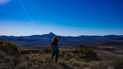 myself a human being on top of a high mountain after hiking it in south africa with sky and the kompaßberg in the background