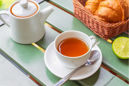 紅茶のカップとティーポット。クロワッサンが盛り付けられたかご。