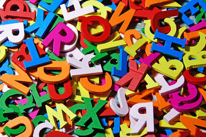 Formatfüllend bunte, aus Holz ausgesägte Buchstaben.