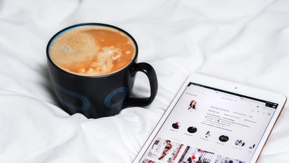 Kaffetasse neben Tablet mit geöffneter Instagram-Ansicht