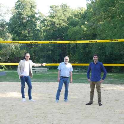 Der Bürgermeister, der Leiter Fachbereich Umwelt und Herr Wiemann von LH-Marketing stehen auf dem neuen Beachvolleyballfeld am Klutensee