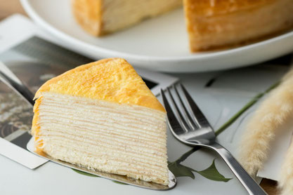 白のお皿に盛りつけられたイチゴのホールケーキ。ナイフとフォーク。グラスに注がれたアイスティー。ミントの葉。