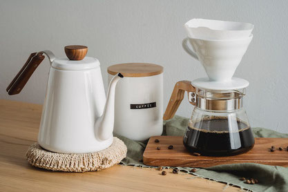 オレンジのガーベラ、バラの花。コーヒーの入ったカップ&ソーサ。メモ、ボールペン、はさみ、封筒。