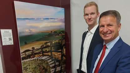 Landrat Michael Stickeln (rechts) und Fotograf Noah Gievers bei der Vernissage vor einem Bild vom Desenberg. Foto: Kreis Höxter