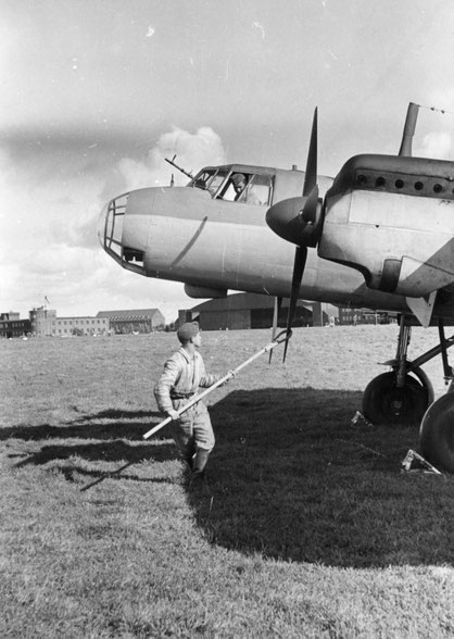 Flugzeug, im Hintergrund der Flugplatztower und Unterkunftsgebäude. Quelle: MUZEUM POWSTANIA WARSZAWSKIEGO